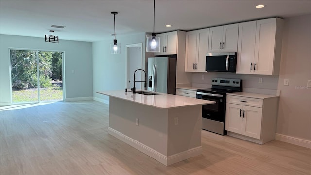 7052 Legion St, Port Charlotte, FL 33981 - kitchen with stainless steel appliances, light wood-style flooring, light countertops, white cabinets, and a center island with sink
