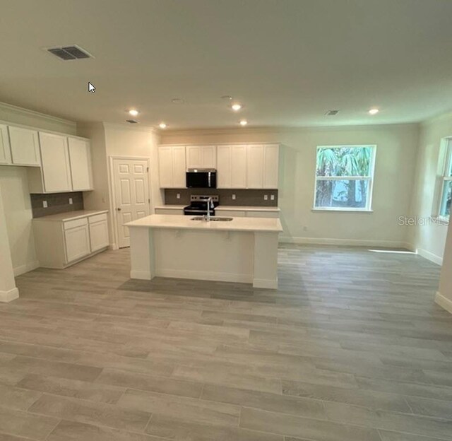 41 Fountain Gate Ln, Palm Coast, FL 32137 - kitchen with appliances with stainless steel finishes, a kitchen island with sink, white cabinetry, open floor plan, and recessed lighting