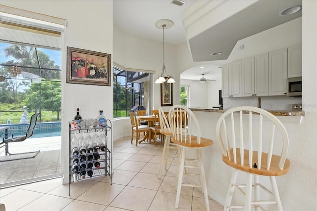 2329 Como St, Port Charlotte, FL 33948 - kitchen with stainless steel microwave, a ceiling fan, light tile patterned floors, pendant lighting, and a kitchen breakfast bar