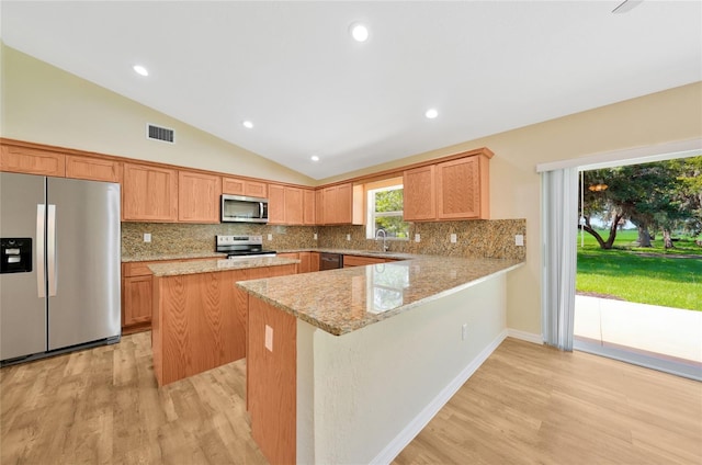 3993 NE Bobay Rd, Arcadia, FL 34266 - kitchen with stainless steel appliances, vaulted ceiling, light wood finished floors, decorative backsplash, and a center island