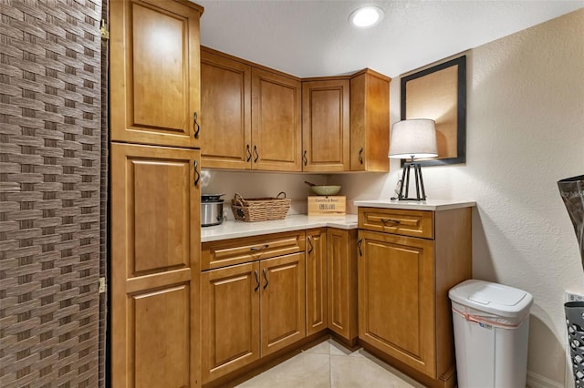 1250 W Marion Ave Unit 333, Punta Gorda, FL 33950 - kitchen with brown cabinets, light countertops, light tile patterned floors, and a textured wall