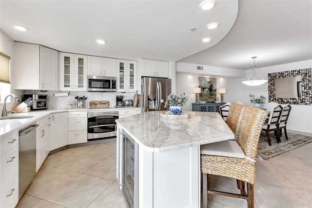1250 W Marion Ave Unit 333, Punta Gorda, FL 33950 - kitchen with appliances with stainless steel finishes, a breakfast bar area, a kitchen island, tasteful backsplash, and light tile patterned flooring