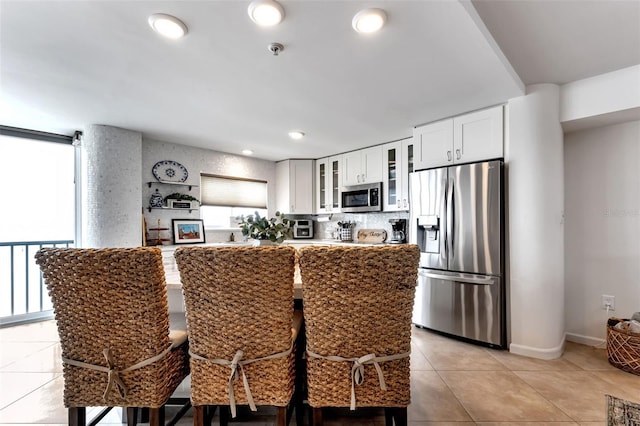 1250 W Marion Ave Unit 333, Punta Gorda, FL 33950 - kitchen featuring stainless steel appliances, light tile patterned floors, glass insert cabinets, white cabinetry, and a breakfast bar