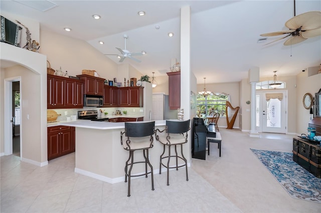 3824 Dominic St, North Port, FL 34288 - kitchen featuring appliances with stainless steel finishes, ceiling fan, reddish brown cabinets, light countertops, and high vaulted ceiling