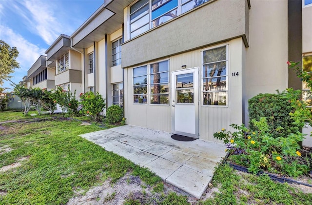 2437 Harbor Blvd Unit 114, Port Charlotte, FL 33952 - doorway to property with a yard, a patio area, and stucco siding