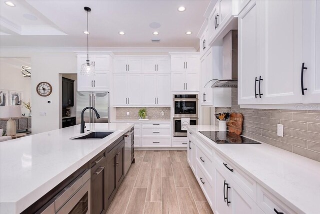 3800 Carupano Ct, Punta Gorda, FL 33950 - kitchen with built in appliances, white cabinetry, wall chimney exhaust hood, decorative light fixtures, and tasteful backsplash