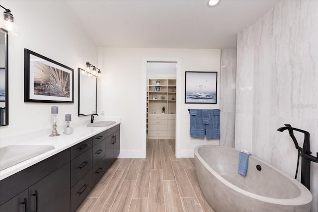3800 Carupano Ct, Punta Gorda, FL 33950 - bathroom with double vanity, a freestanding tub, wood tiled floors, and a spacious closet