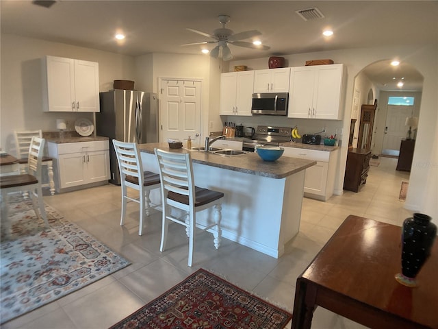 25228 E Lenox Cir, Punta Gorda, FL 33950 - kitchen featuring stainless steel appliances, arched walkways, ceiling fan, dark countertops, and white cabinetry