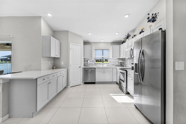 1731 NW 24th Pl, Cape Coral, FL 33993 - kitchen with stainless steel appliances, decorative backsplash, a peninsula, light countertops, and light tile patterned flooring