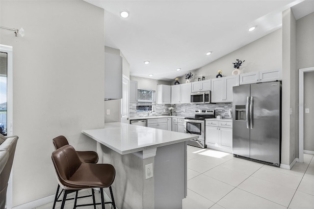1731 NW 24th Pl, Cape Coral, FL 33993 - kitchen with stainless steel appliances, a breakfast bar, decorative backsplash, light countertops, and a peninsula