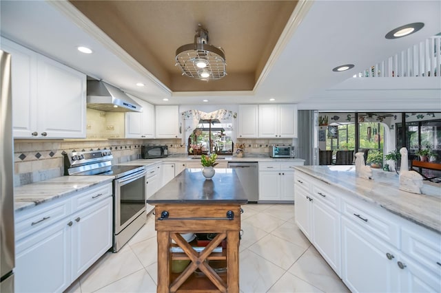 1418 Grebe Dr, Punta Gorda, FL 33950 - kitchen with appliances with stainless steel finishes, wall chimney exhaust hood, a tray ceiling, backsplash, and light stone countertops