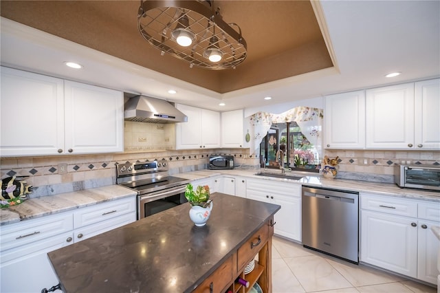 1418 Grebe Dr, Punta Gorda, FL 33950 - kitchen with appliances with stainless steel finishes, wall chimney exhaust hood, a tray ceiling, tasteful backsplash, and light stone countertops