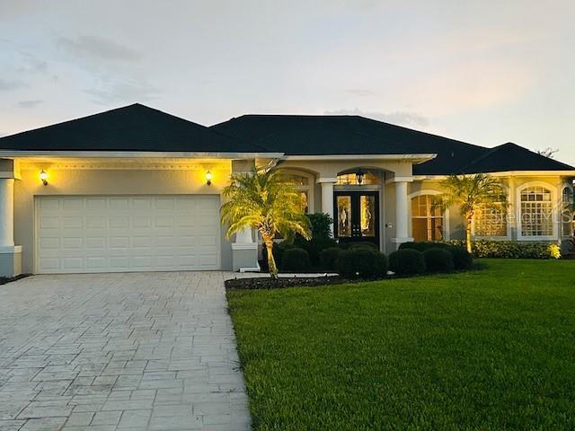 260 Rotonda Blvd E, Rotonda West, FL 33947 - ranch-style home with decorative driveway, french doors, a garage, a front yard, and stucco siding