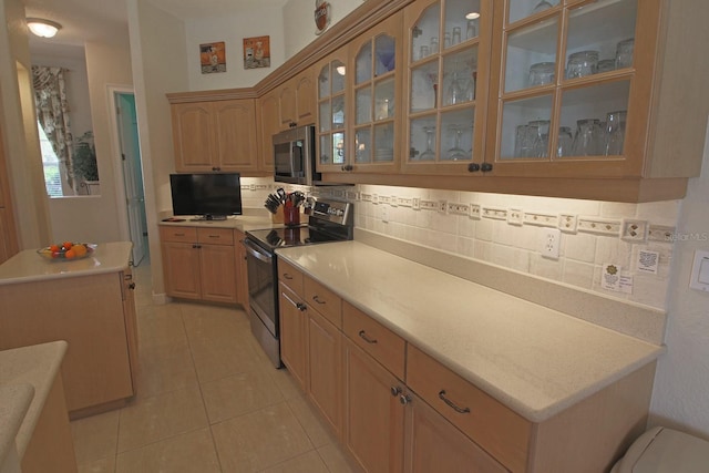 260 Rotonda Blvd E, Rotonda West, FL 33947 - kitchen with appliances with stainless steel finishes, decorative backsplash, light tile patterned flooring, and glass insert cabinets