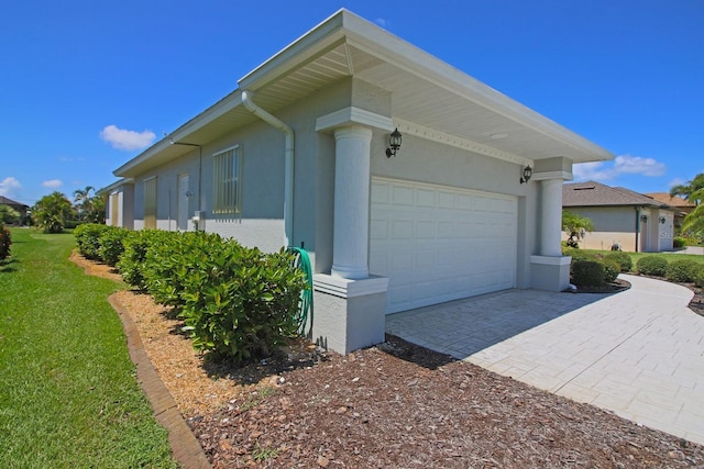 260 Rotonda Blvd E, Rotonda West, FL 33947 - view of side of property featuring a garage, driveway, stucco siding, and a lawn