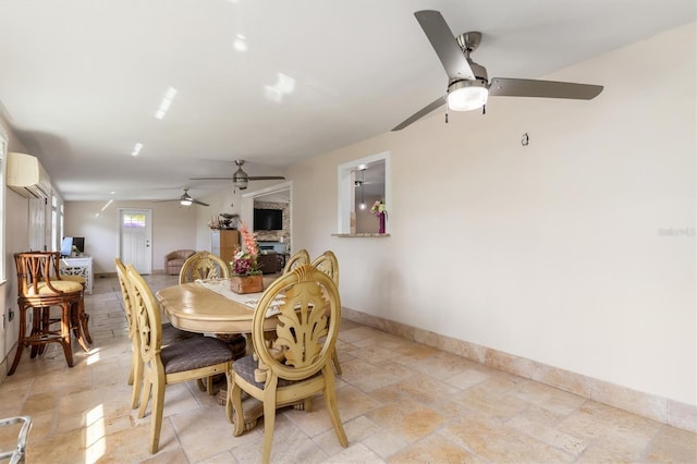 123 Annapolis Ln, Rotonda West, FL 33947 - dining room featuring a ceiling fan, an AC wall unit, a stone fireplace, and light stone finish flooring