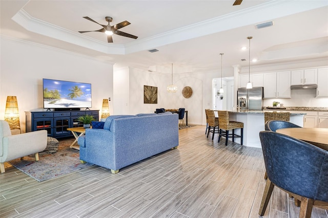 14684 Cherry Blossom Way, Punta Gorda, FL 33955 - living room featuring a tray ceiling, ceiling fan, light wood-style floors, and crown molding