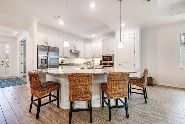 14684 Cherry Blossom Way, Punta Gorda, FL 33955 - kitchen featuring stainless steel appliances, wood finish floors, a breakfast bar area, a tray ceiling, and ornamental molding