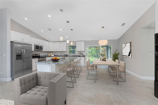 4863 Las Almanos Ave, North Port, FL 34288 - kitchen with stainless steel appliances, lofted ceiling, white cabinets, a breakfast bar, and recessed lighting