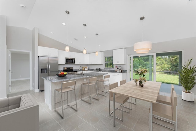 4863 Las Almanos Ave, North Port, FL 34288 - kitchen featuring stainless steel appliances, a kitchen island with sink, a breakfast bar area, healthy amount of natural light, and high vaulted ceiling