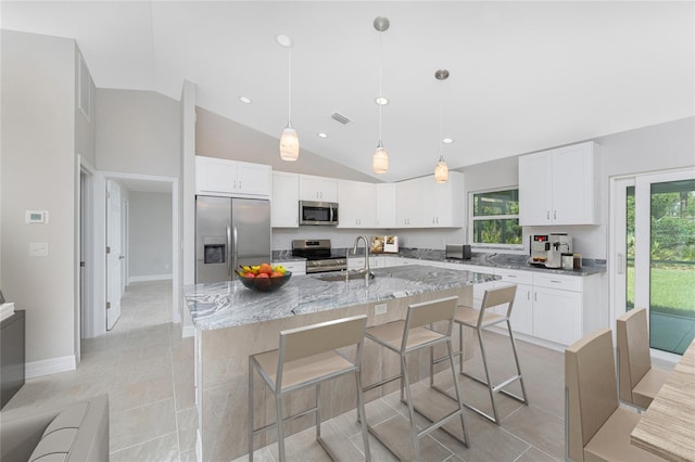 4863 Las Almanos Ave, North Port, FL 34288 - kitchen featuring appliances with stainless steel finishes, light stone countertops, vaulted ceiling, white cabinets, and a kitchen breakfast bar