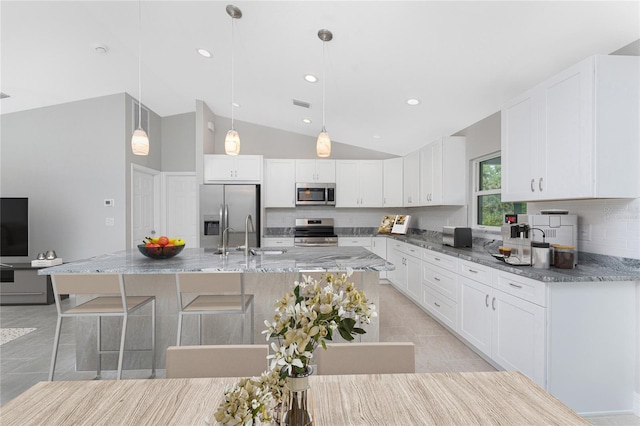 4863 Las Almanos Ave, North Port, FL 34288 - kitchen with appliances with stainless steel finishes, backsplash, lofted ceiling, white cabinetry, and light stone counters