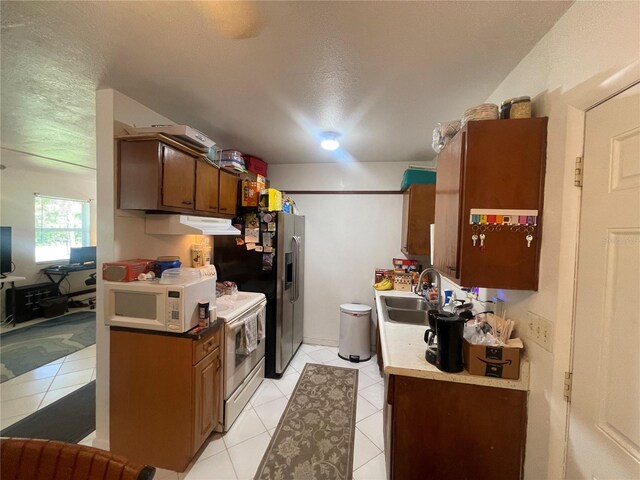 2336 Picnic St, Port Charlotte, FL 33952 - kitchen with white appliances, under cabinet range hood, light tile patterned flooring, light countertops, and a textured ceiling