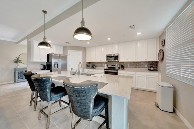 12425 Ghiberti Cir Unit 101, Venice, FL 34293 - kitchen with appliances with stainless steel finishes, backsplash, white cabinets, a breakfast bar, and recessed lighting