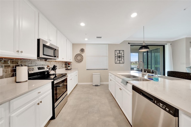 12425 Ghiberti Cir Unit 101, Venice, FL 34293 - kitchen with appliances with stainless steel finishes, decorative backsplash, recessed lighting, light stone counters, and white cabinets