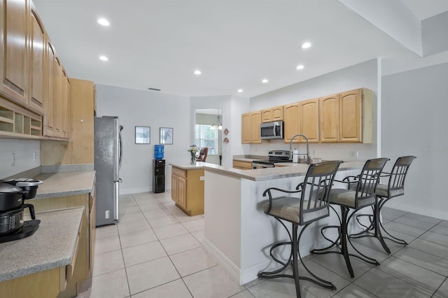 3116 SW 16th Pl, Cape Coral, FL 33914 - kitchen featuring appliances with stainless steel finishes, a kitchen bar, a kitchen island, light tile patterned flooring, and recessed lighting