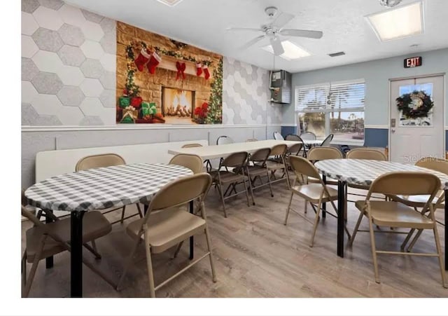 311 Garvin St Unit 301B, Punta Gorda, FL 33950 - dining room featuring wallpapered walls, a ceiling fan, a wainscoted wall, an accent wall, and light wood finished floors
