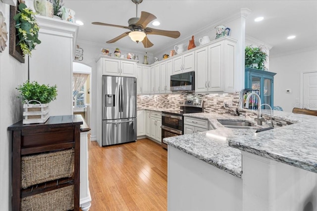233 Durrance St, Punta Gorda, FL 33950 - kitchen featuring stainless steel appliances, ceiling fan, decorative backsplash, light wood finished floors, and ornamental molding