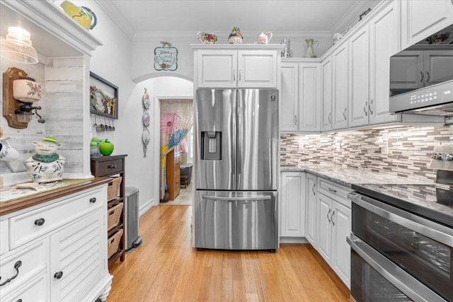 233 Durrance St, Punta Gorda, FL 33950 - kitchen with appliances with stainless steel finishes, white cabinetry, light wood-style flooring, tasteful backsplash, and light stone countertops