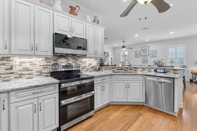233 Durrance St, Punta Gorda, FL 33950 - kitchen with stainless steel appliances, a ceiling fan, a peninsula, light wood-style flooring, and backsplash