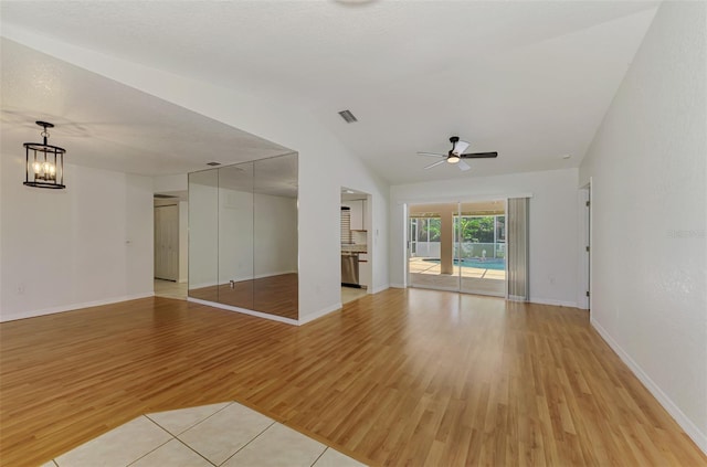 510 Border St, Port Charlotte, FL 33953 - unfurnished living room with light wood-style flooring, ceiling fan, lofted ceiling, and a chandelier