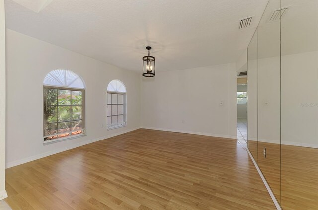 510 Border St, Port Charlotte, FL 33953 - unfurnished room featuring light wood finished floors, healthy amount of natural light, and a chandelier