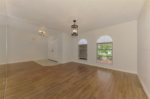 510 Border St, Port Charlotte, FL 33953 - spare room featuring light wood finished floors, a textured ceiling, and a chandelier