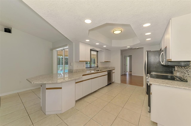 510 Border St, Port Charlotte, FL 33953 - kitchen with a peninsula, dishwasher, a raised ceiling, light tile patterned floors, and white cabinets