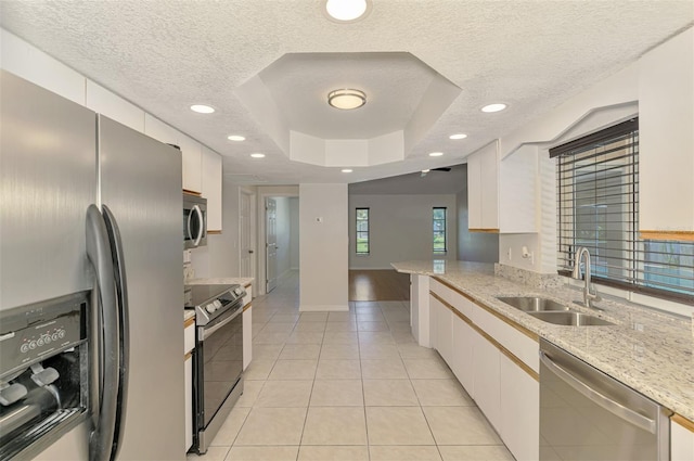 510 Border St, Port Charlotte, FL 33953 - kitchen featuring stainless steel appliances, a textured ceiling, light tile patterned floors, white cabinetry, and a raised ceiling