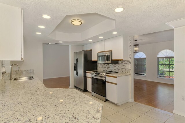 510 Border St, Port Charlotte, FL 33953 - kitchen with stainless steel appliances, light tile patterned flooring, a tray ceiling, white cabinetry, and decorative backsplash