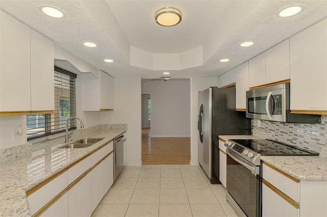 510 Border St, Port Charlotte, FL 33953 - kitchen with appliances with stainless steel finishes, tasteful backsplash, light tile patterned floors, a tray ceiling, and light stone counters