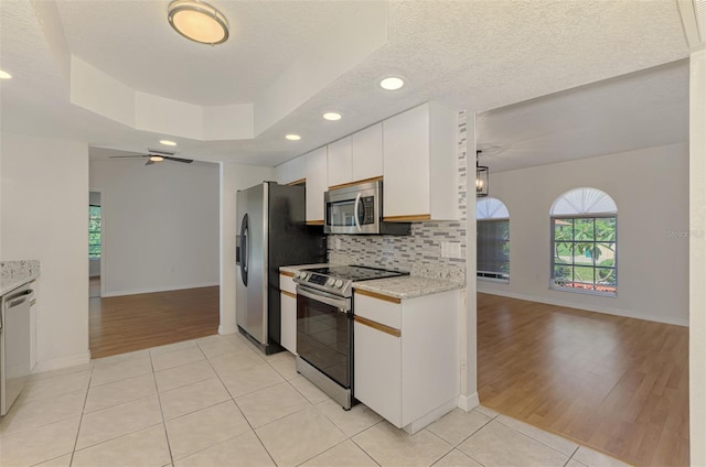 510 Border St, Port Charlotte, FL 33953 - kitchen with stainless steel appliances, light tile patterned floors, white cabinets, decorative backsplash, and recessed lighting