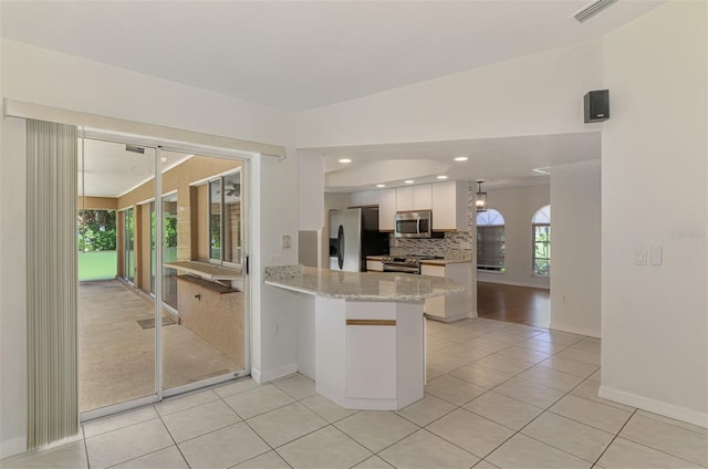 510 Border St, Port Charlotte, FL 33953 - kitchen with appliances with stainless steel finishes, a peninsula, light tile patterned floors, decorative backsplash, and white cabinetry