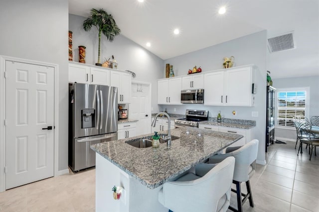 4321 NW 34th Ln, Cape Coral, FL 33993 - kitchen featuring stainless steel appliances, an island with sink, light stone countertops, white cabinets, and light tile patterned flooring