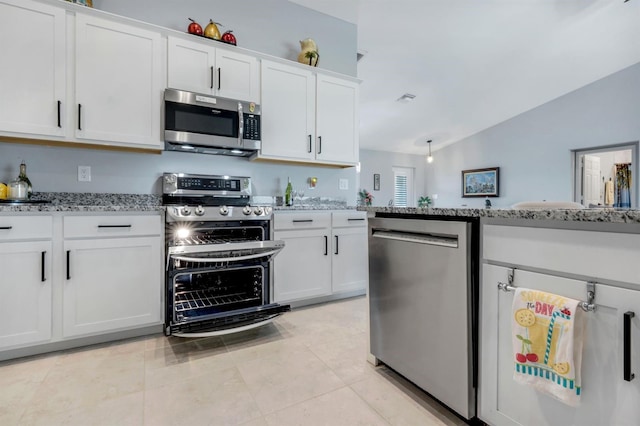 4321 NW 34th Ln, Cape Coral, FL 33993 - kitchen with stainless steel appliances, vaulted ceiling, white cabinetry, light stone countertops, and light tile patterned floors