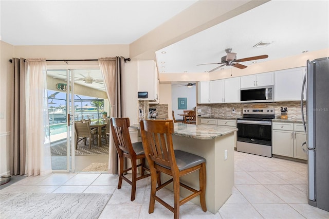 4142 Reif Ct, Port Charlotte, FL 33981 - kitchen featuring appliances with stainless steel finishes, ceiling fan, light stone counters, a peninsula, and backsplash