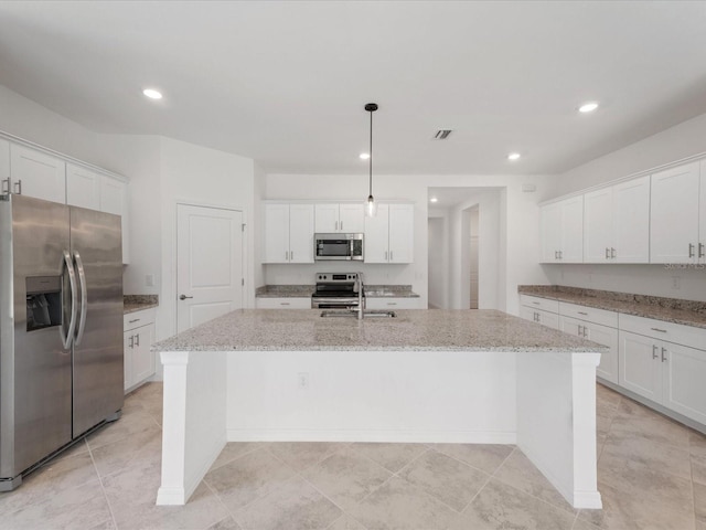 2161 Gardenia Ave, Port Charlotte, FL 33953 - kitchen with appliances with stainless steel finishes, a center island with sink, white cabinets, recessed lighting, and light stone counters