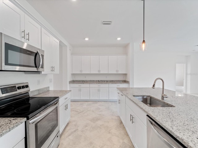 2161 Gardenia Ave, Port Charlotte, FL 33953 - kitchen with stainless steel appliances, white cabinets, hanging light fixtures, light stone countertops, and recessed lighting
