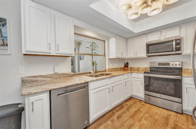 1478 Harmony Dr, Port Charlotte, FL 33952 - kitchen with stainless steel appliances, white cabinets, light wood-type flooring, and light stone countertops
