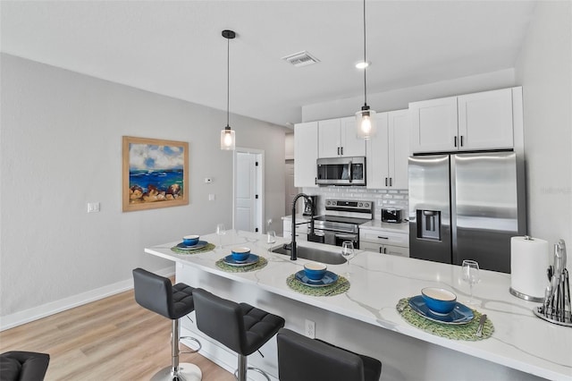 9155 Agate St, Port Charlotte, FL 33981 - kitchen with appliances with stainless steel finishes, white cabinets, a breakfast bar area, light stone counters, and backsplash